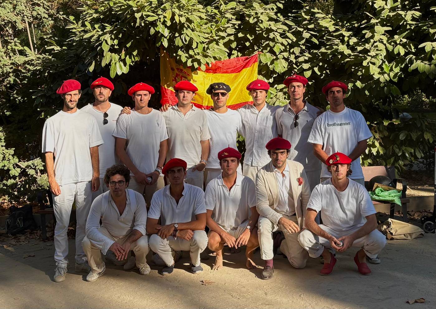Trece miembros del Club vestidos de blanco y con boina roja, ante una bandera de España